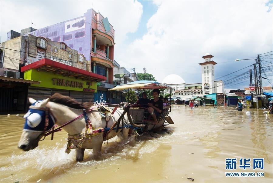 1月26日，在印度尼西亚万隆，人们涉水出行。 当日，印度尼西亚万隆部分区域受洪水侵袭，致使数千房屋被淹，数百民众从住所撤离。 新华社发（赛普蒂安贾尔摄）