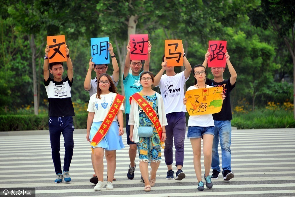 山东聊城:大学生街头举牌宣传文明过马路