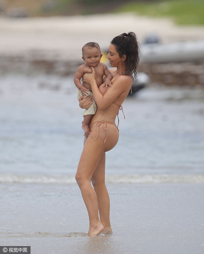 当地时间8月18日,金·卡戴珊(Kim Kardashian)带女儿小西北和儿子沙滩玩耍,卡戴珊身穿裸色系带比基尼,女儿与妈妈同款可爱十足,在沙滩上卡戴珊全程呵护幼子母爱爆棚,然而抢镜的还是翘臀。图为卡戴珊抱幼子爱意浓浓。