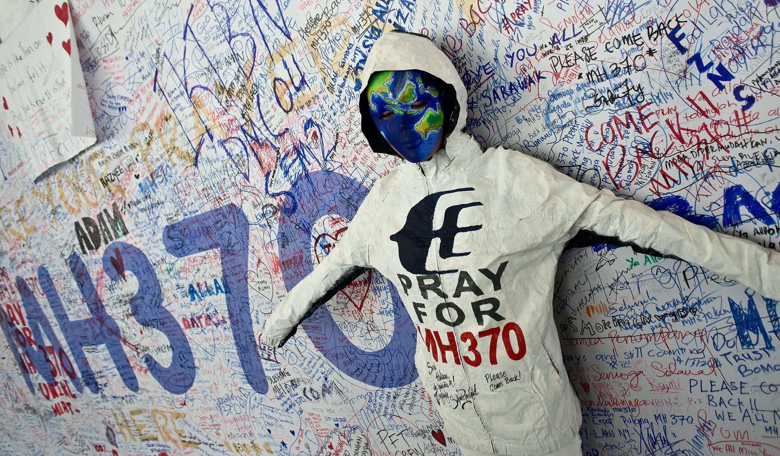当地时间2014年3月17日，马来西亚吉隆坡国际机场，民众持续为马航失联航班乘客祈福。一名艺术家站在祈福留言板前。