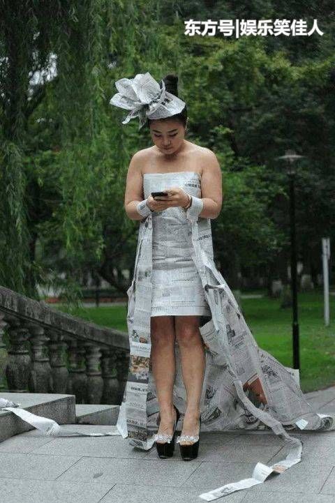 女子洗完澡,穿着用报纸做成的裙子到广场乘凉,引来游客拍照