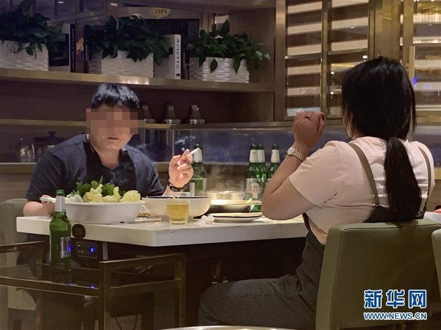 5月27日,北京东城区某餐厅内,一位食客(左)在室内吸烟(手机拍摄)。