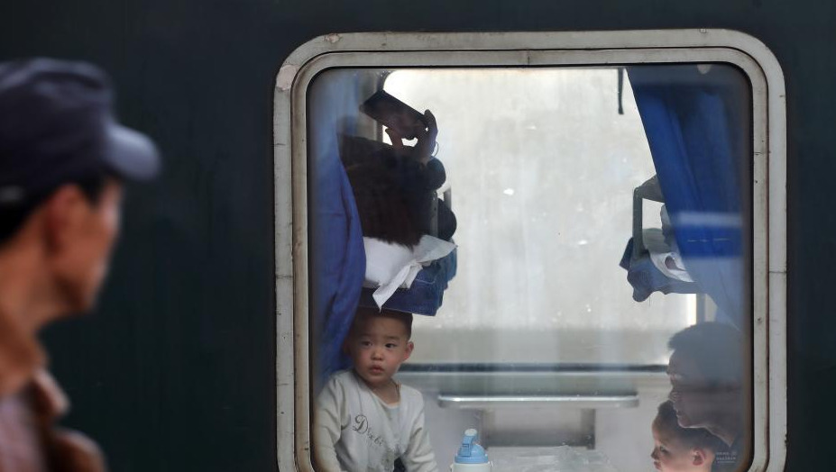 1月24日，透过停靠在南京火车站的列车车窗，车内的乘客或站、或坐、或沉思。随着春节的临近，越来越多的民众带上行李，踏上旅途。