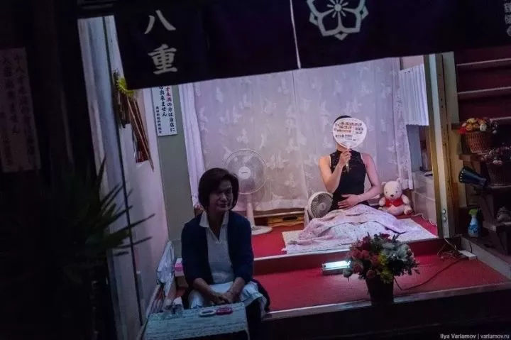 飞田新地的运营模式是，在每间店门口都会坐着一名女生和一名妈妈桑，女生穿着各种诱人服饰，面前还会打上灯光，就像是橱窗展示一样，等待客人。