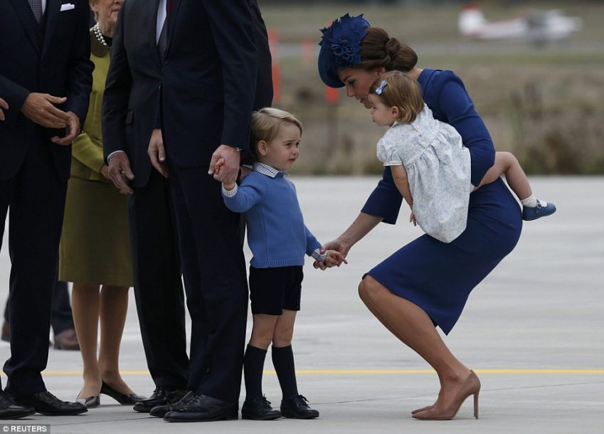 夏洛特则穿着一袭漂亮的白色印花洋装，脚踩蓝色鞋，头上也系了蓝色蝴蝶结。一旁的大人们轻声哄着这位小公主，她似乎为此相当开心，丝毫没有受到长达10小时的航班影响。