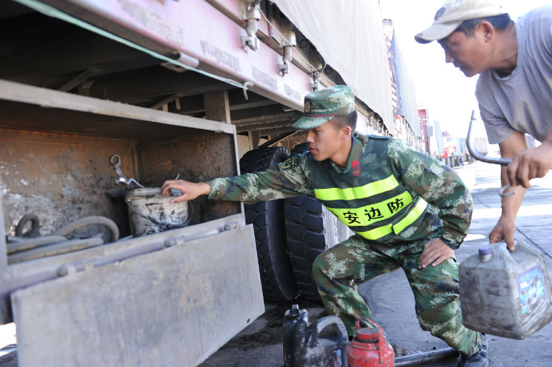 边防检查战士冒着酷暑对入境车辆仔细认真地进行检查