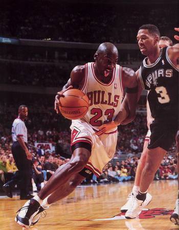 来看乔丹过人，他的大手牢牢地控制住球，另外一只手则起到阻碍防守队员的作用。同时，他的标志性伸舌头也会在运球的时候展现出来。