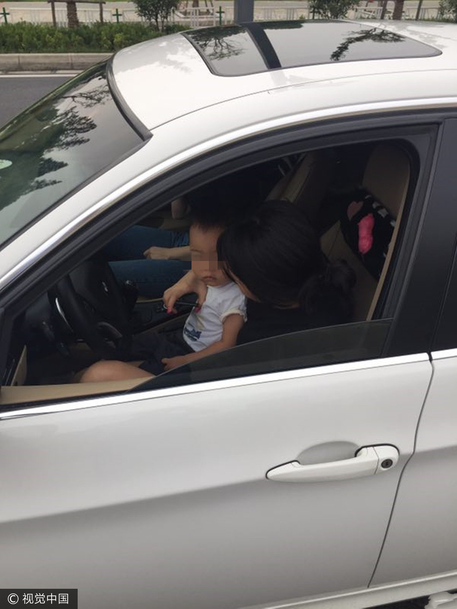 女司机将孩子抱怀里 边哄孩子边开车