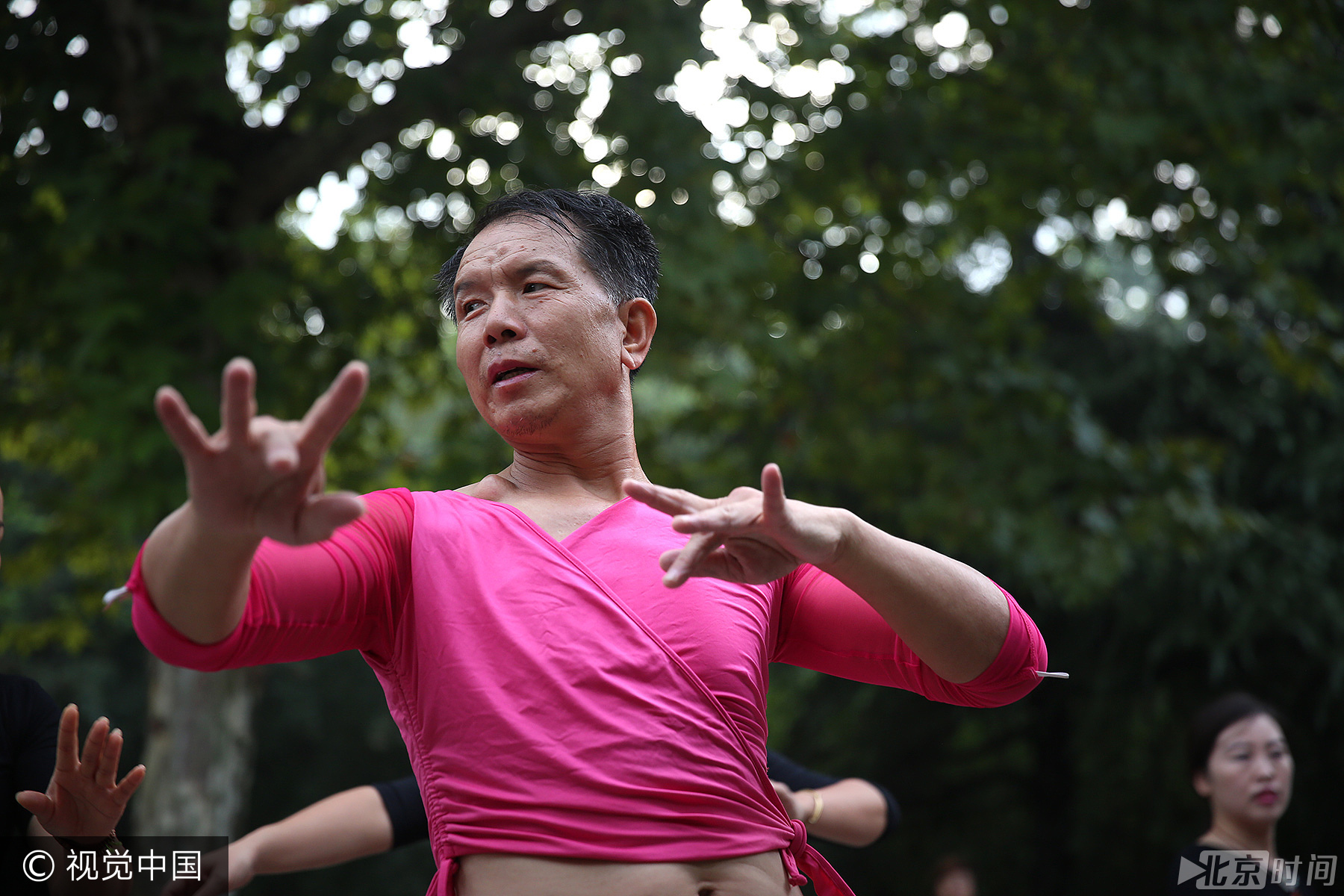 图为正在跳舞的姜克俊身后，有路人投来了“不一样”的眼光。