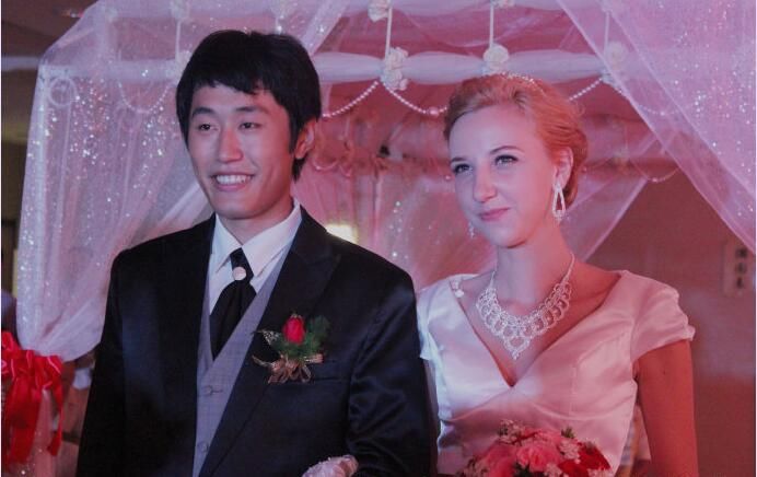 在婚礼上,美丽动人的新娘很是幸福,而旁边的中国小伙更是笑得合不拢嘴