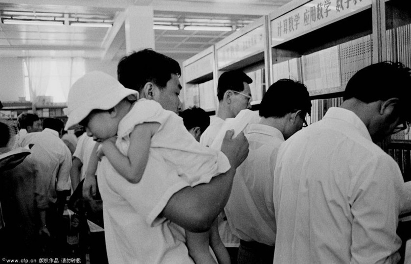 1983年6月，北京王府井新华书店，抱着娃娃的年轻父母前来买各类课本或参考书。时兴文凭了。许多文革中耽误了学业的回城知青，不得不肩挑生活和补学历两副重担。