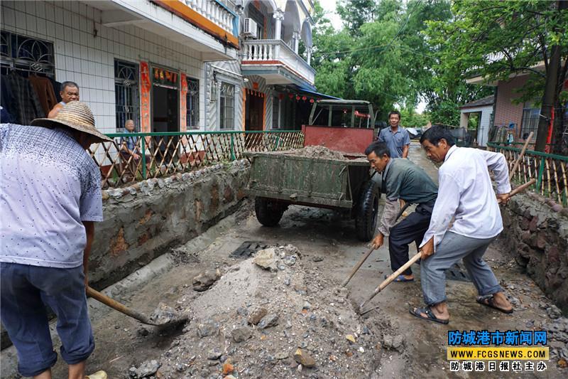 6月8日,在东兴市江平镇巫头村的村道上,村民在停雨间隙清理道路上的