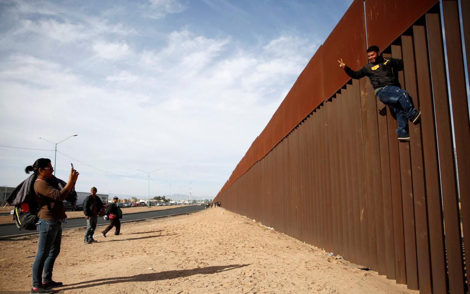 当地时间2018年11月19日，墨西哥墨西卡利，中美洲移民在美墨边境逗留，试图攀爬边境隔离墙。
