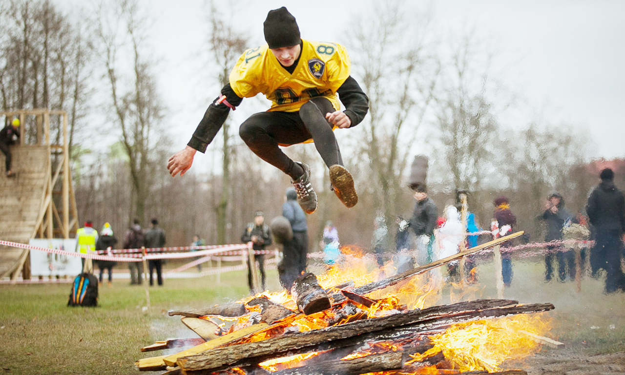 完成它你将获得极大地乐趣。但是在参加这项障碍赛之前，你必须通过PIT测试，即一个高强度的挑战，包括壶铃摆动、跳箱立卧撑和卧推，从而判断你能否完成这项比赛。图为选手跳过火堆。