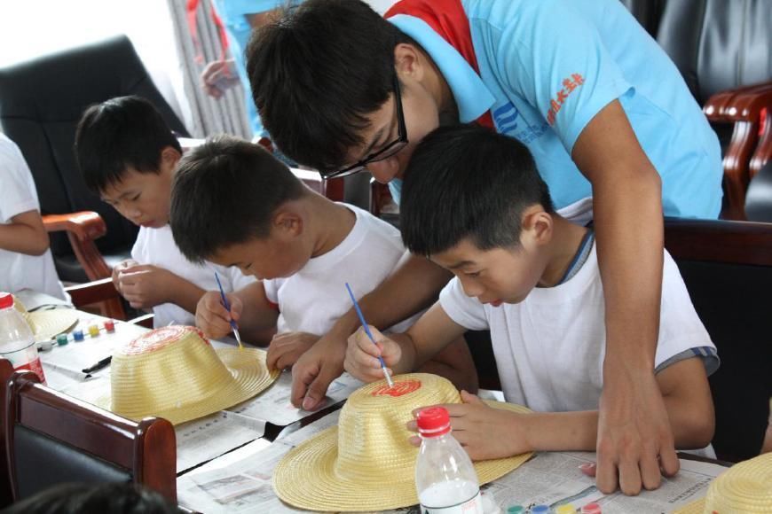 大学生志愿者教小学生手绘草帽赠环卫工人
