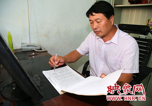 张建设认真核对被帮扶贫苦户的工资表,不让一个贫苦户吃亏