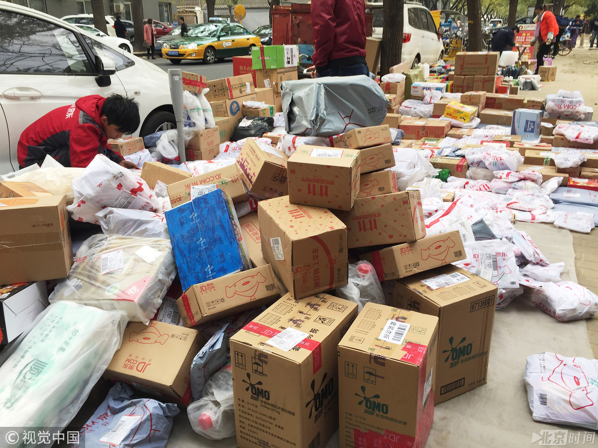 11月12日，北京一高校北侧的一处公园空地上，能见到很多快递公司在此处分拣快递，地上的众多包裹堆积在此处，最高的有一米多。图/视觉中国