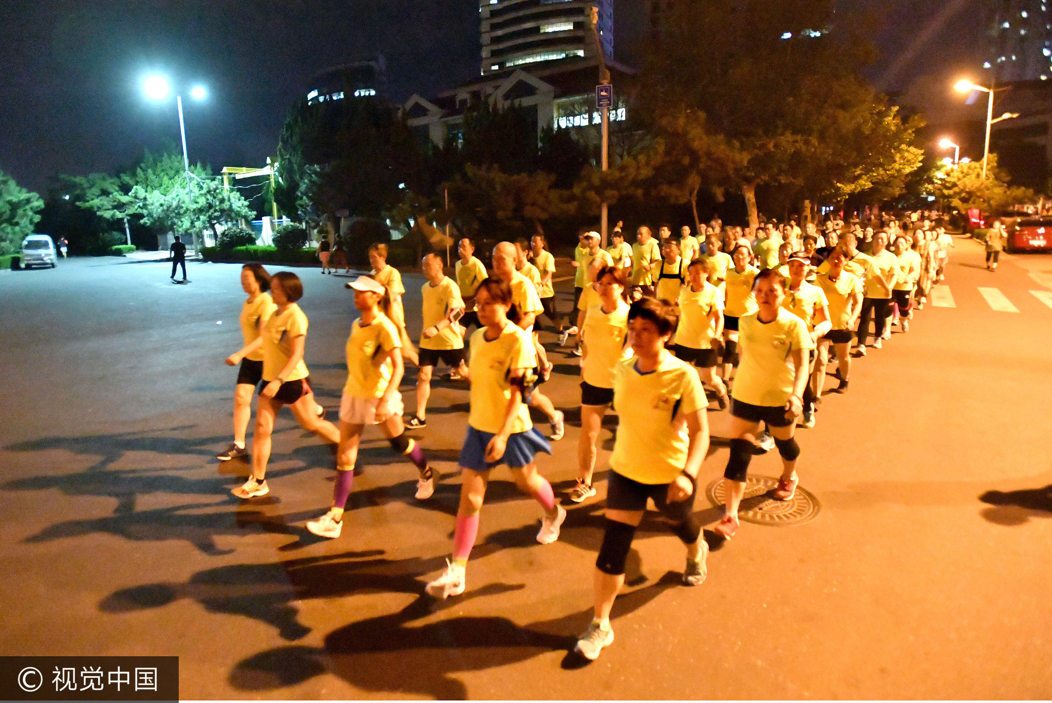 25日，青岛。八大峡广场周边部分路段为保障“暴走团”健身居民安全，开始在夜间施行机动车限行，避免人车混行。图为弹性限行后，“暴走团”在没有车的道路上大步行进。