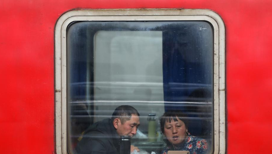 1月24日，透过停靠在南京火车站的列车车窗，车内的乘客或站、或坐、或沉思。随着春节的临近，越来越多的民众带上行李，踏上旅途。