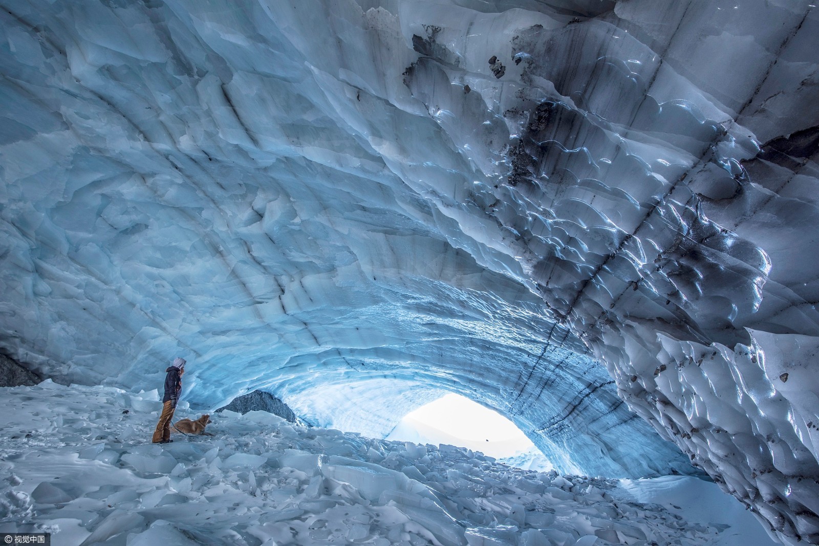 女孩与爱犬徒步深入冰窟探索洞内冰雪世界