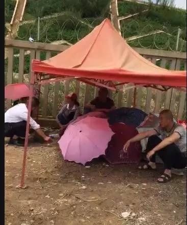 角落撑起了一个临时帐篷，几把彩色的雨伞围出相对私密干净的空间。那里静静地躺着一对母子，在大雨中，他们再也没能回家。