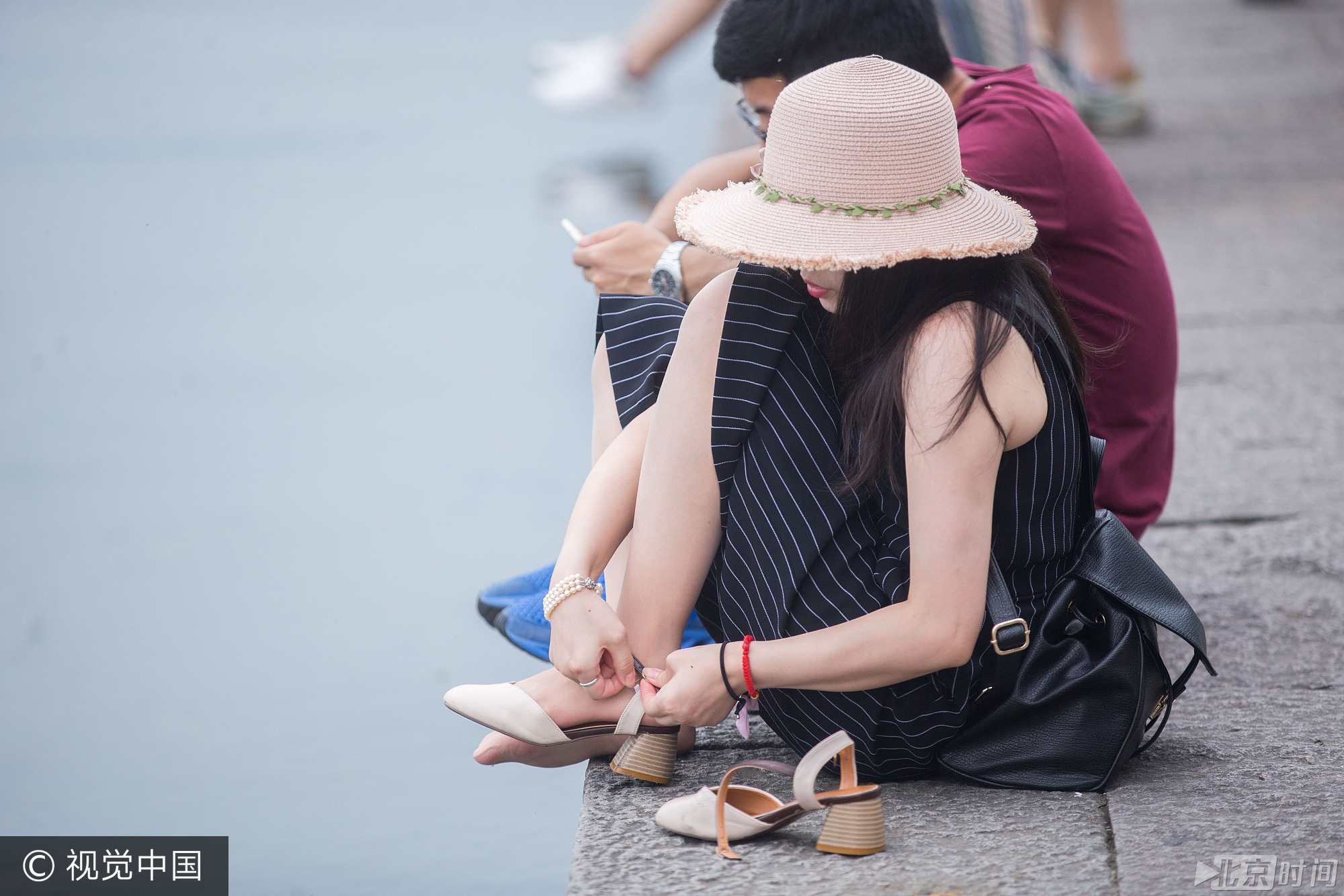 当天也有景区的工作人员在一旁劝导游客不要将脚伸进西湖里。一名女游客在听到劝导声后，穿起了鞋子准备离开。