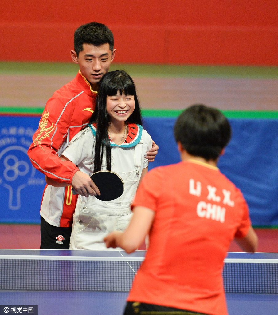 组图-奥运冠军示范表演 张继科搂美女打球