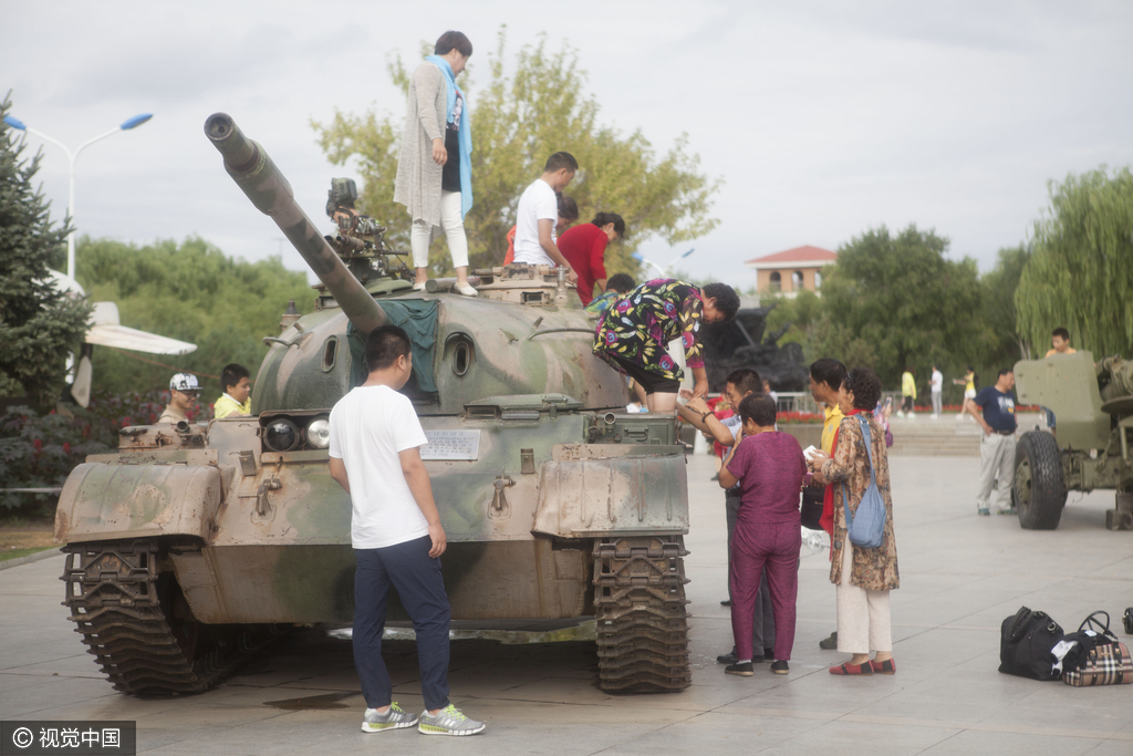 2016年08月10日，黑龙江省齐齐哈尔市，广场现坦克飞机，市民组团攀爬合影。