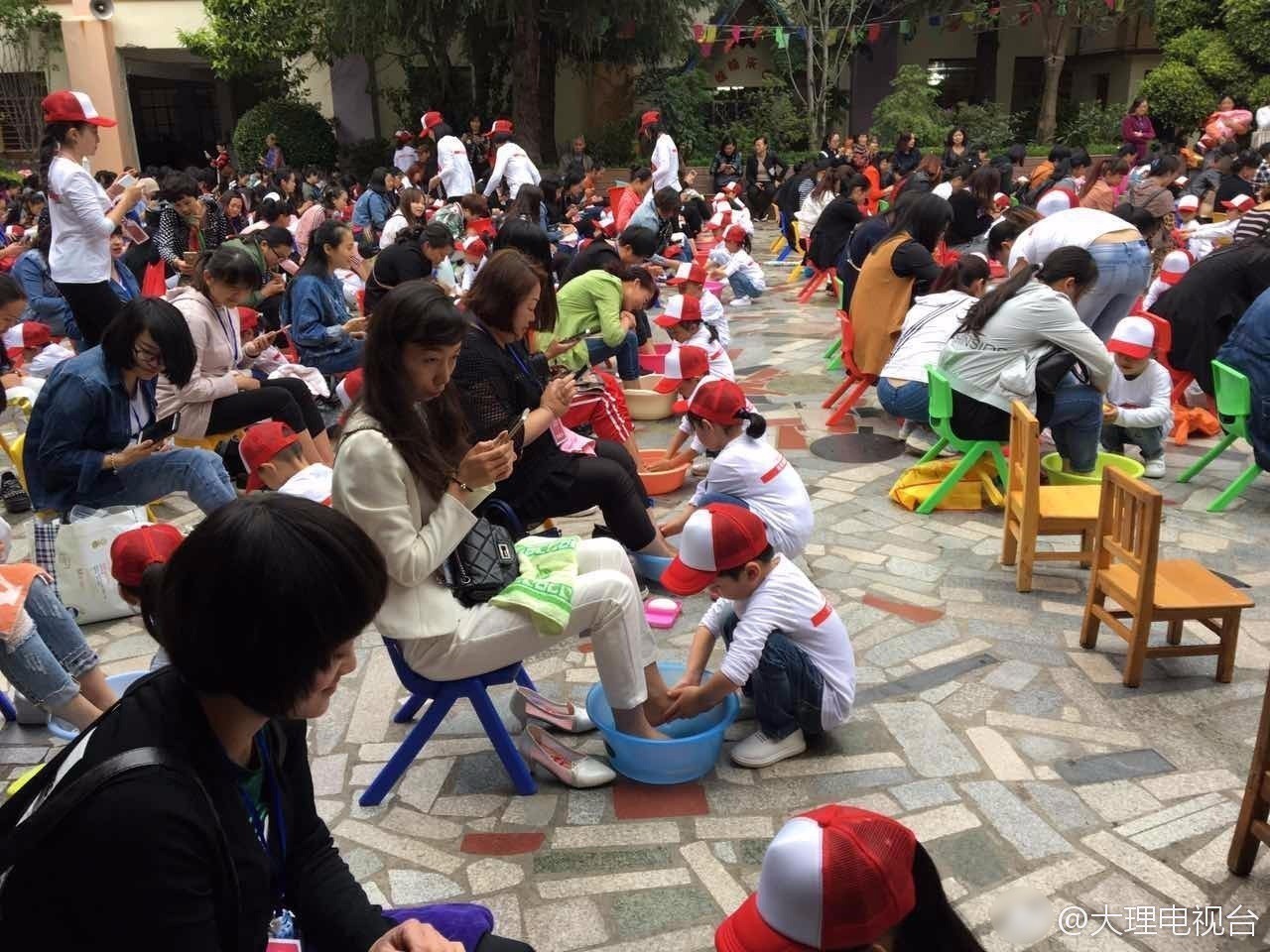 幼儿园孩子为母亲洗脚 妈妈们却只顾低头玩手机 幼儿园孩子为母亲洗脚 妈妈们却只顾低头玩手机