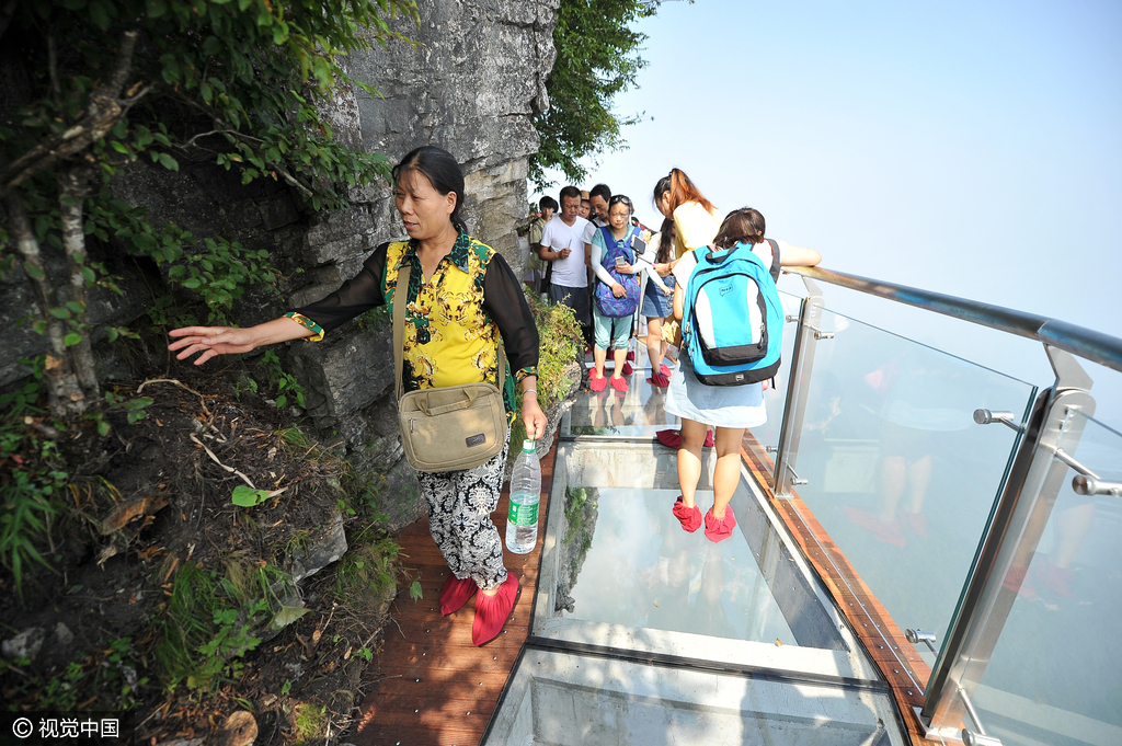 游客们在盘龙崖玻璃栈道上游玩拍照。