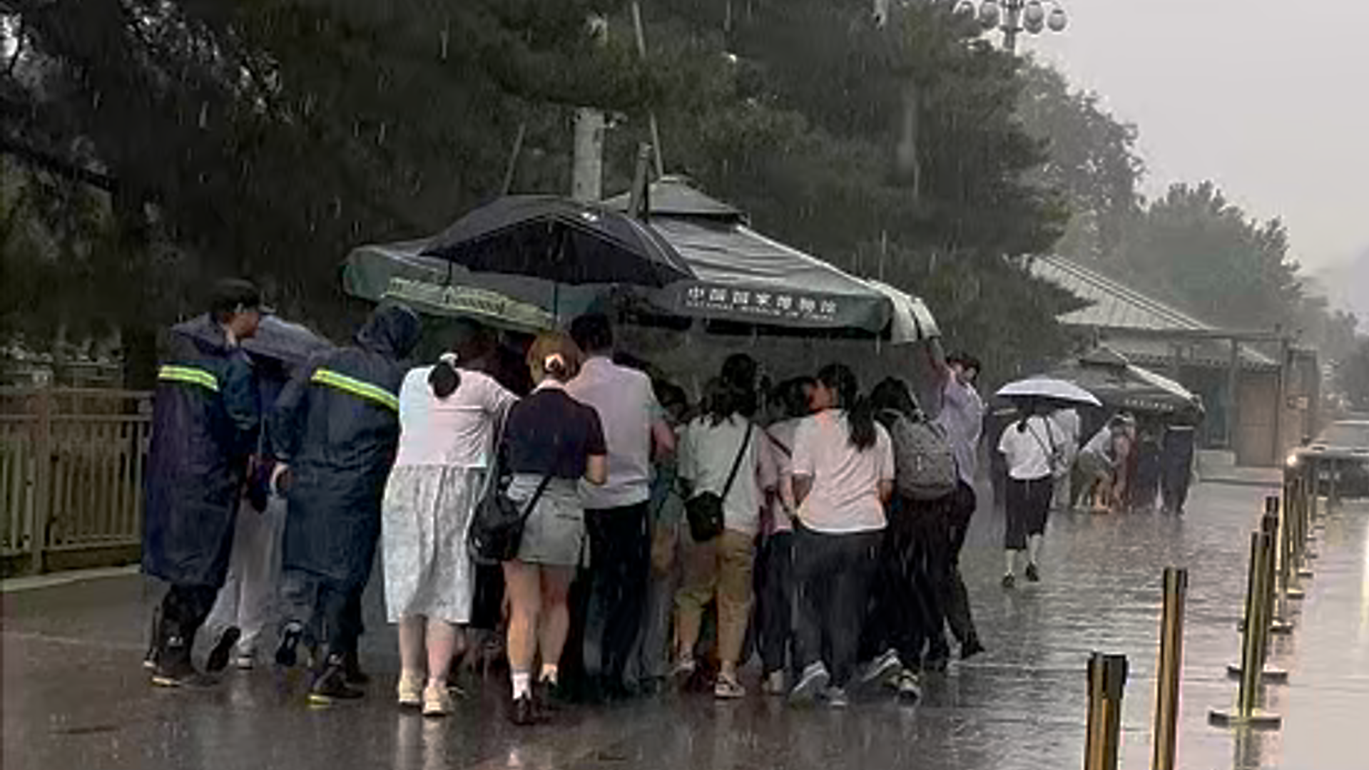 参观国博突遇大雨 工作人员冒雨撑起大伞 将游客们送到地铁站